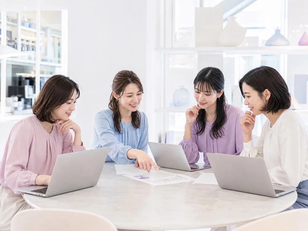 複数の女性がノートパソコンを見ながら、最新のAI情報を共有し合っている様子